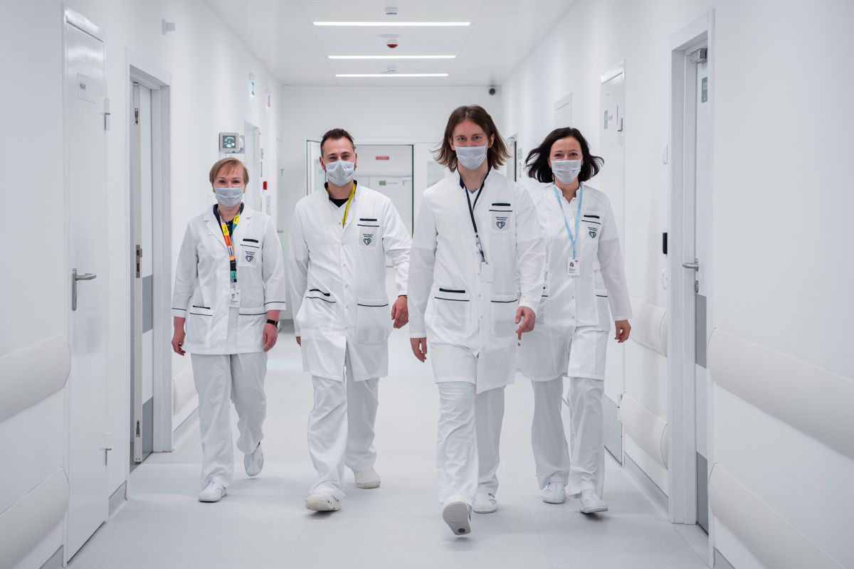 Equipe médica caminhando em corredor de hospital.