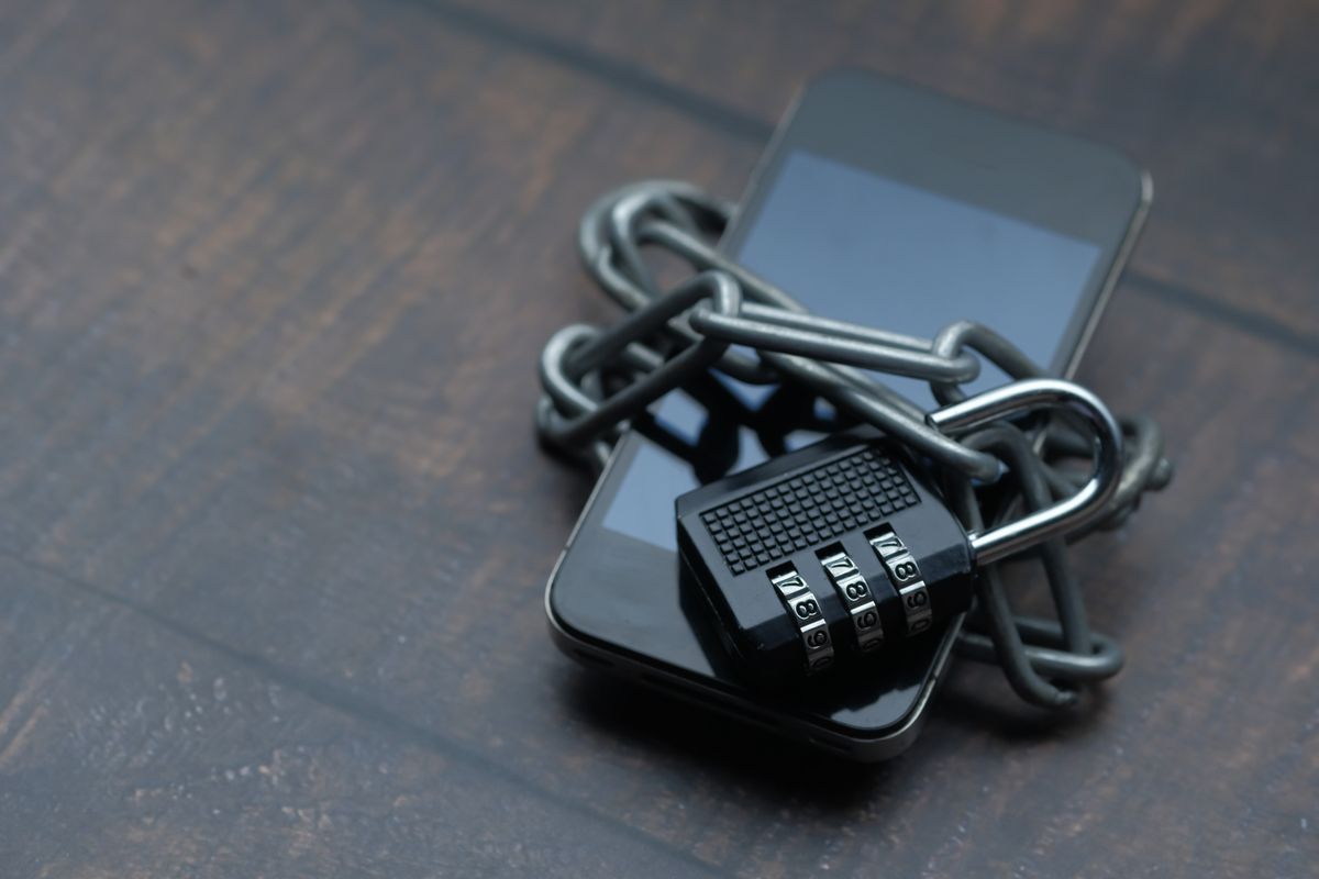 Smartphone protegido por corrente e cadeado, simbolizando segurança de dados.