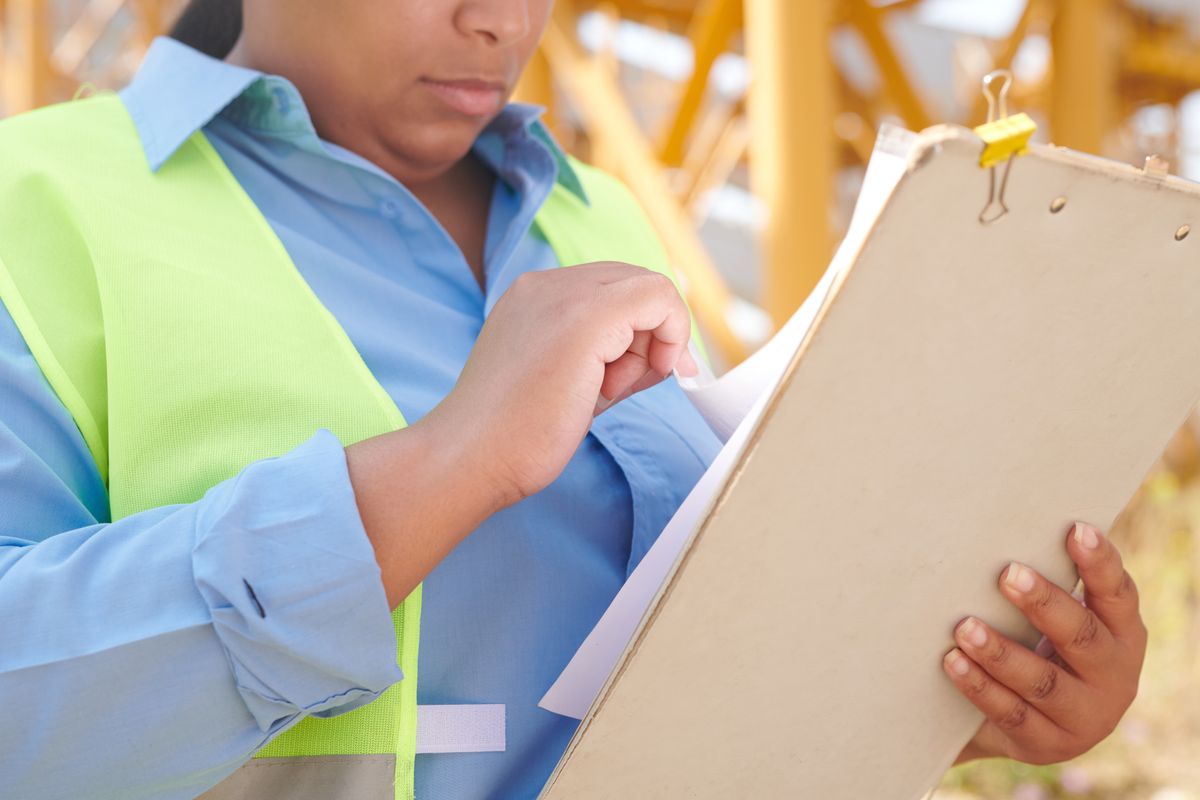 Engenheira revisando documentos técnicos em um canteiro de obras.